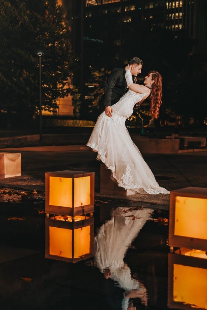 Bride and groom dipping kiss, dramatic night portrait with lantern light and reflection in Indianapolis.