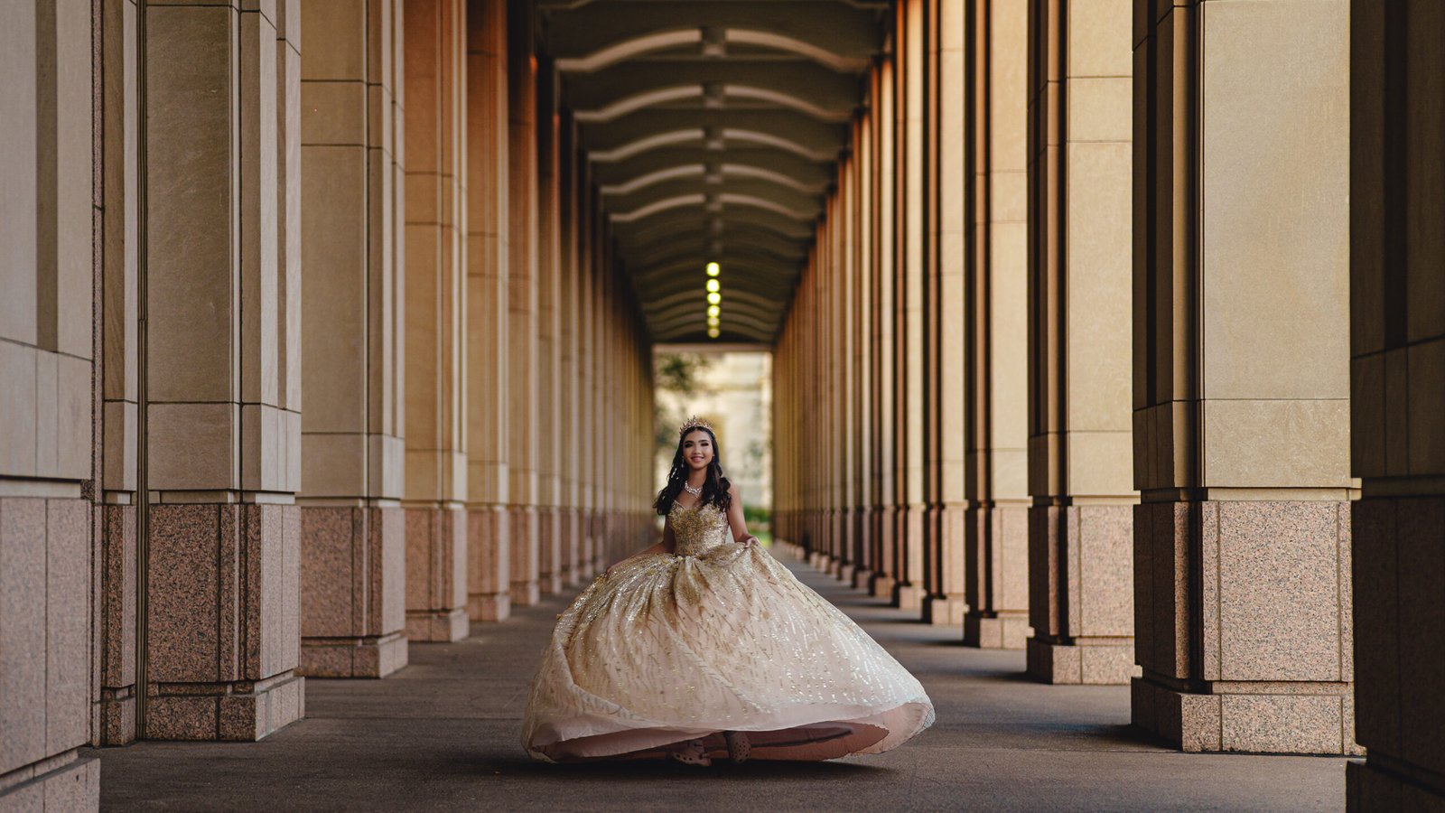 Full-length Quinceanera portrait in sparkling gown, dramatic columns perspective at Indianapolis Canal Walk.