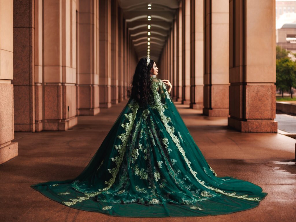 Regal Quinceanera in emerald gown, moody cinematic light under portico columns at the Indianapolis Capitol.