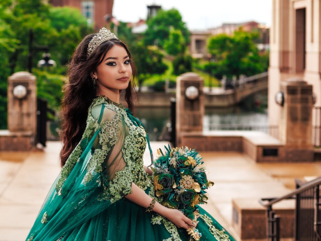 Quinceanera close-up in emerald cape dress near stone bridge, moody urban portrait taken on a rainy day in downtown Indianapolis.