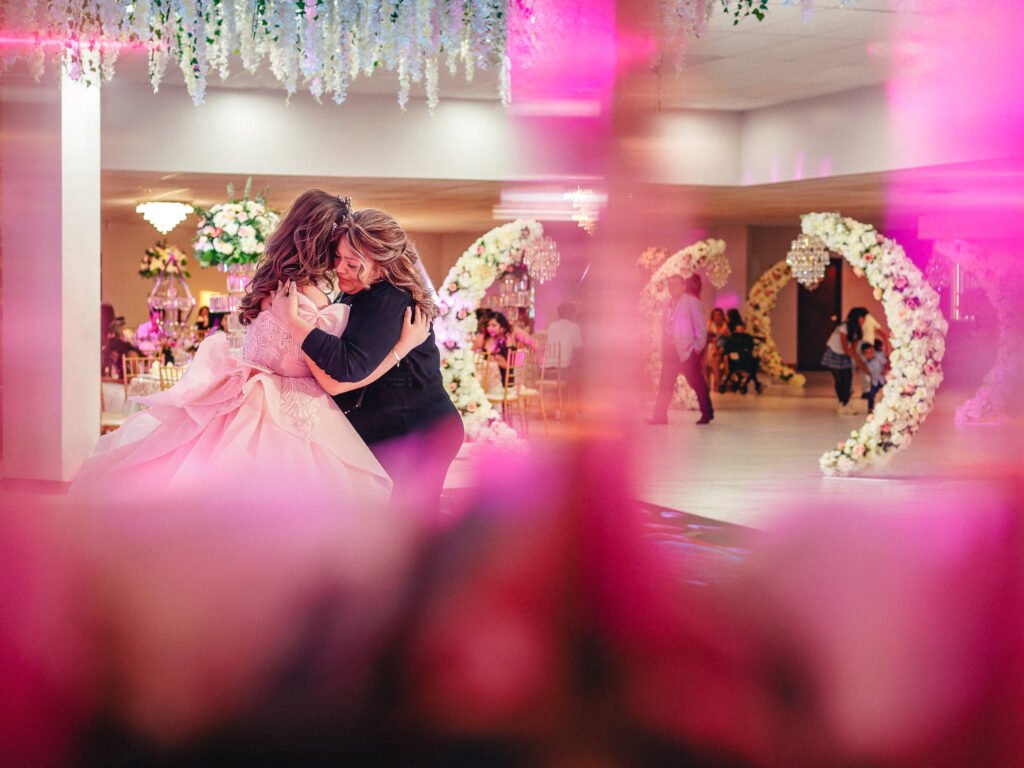 Quinceanera in blush gown, dramatic back bow, cinematic lighting, and elegant floral arches.