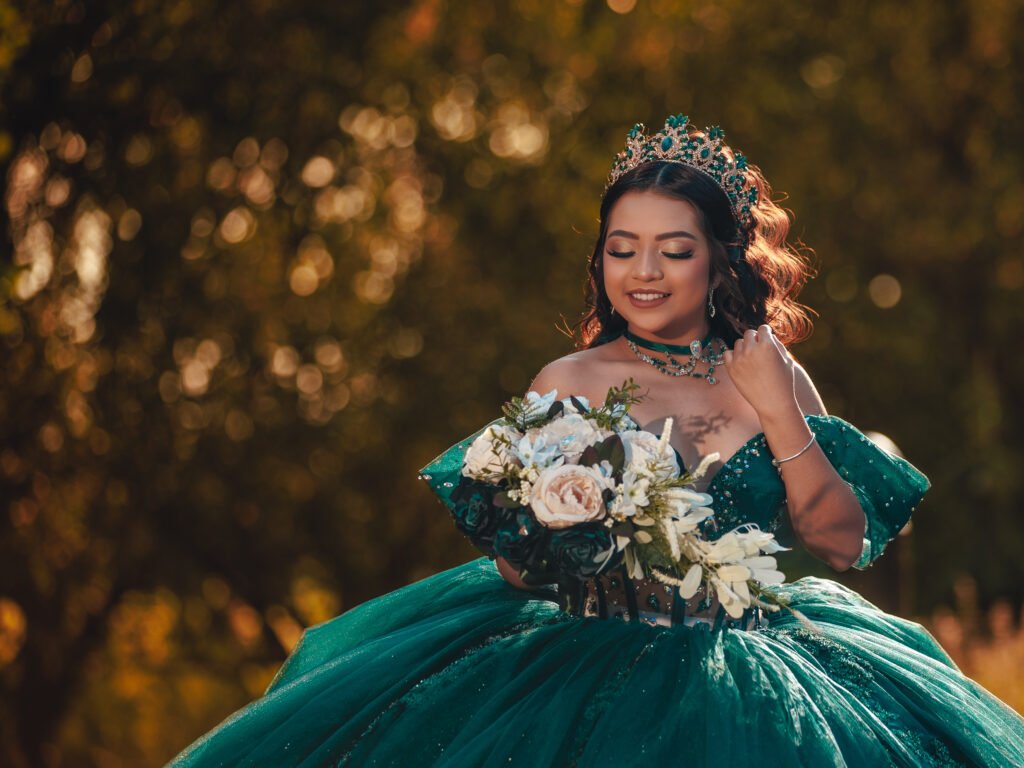 Smiling Quinceanera looking up in emerald dress with bouquet, warm cinematic golden hour light and bokeh background in Carmel, Indiana.