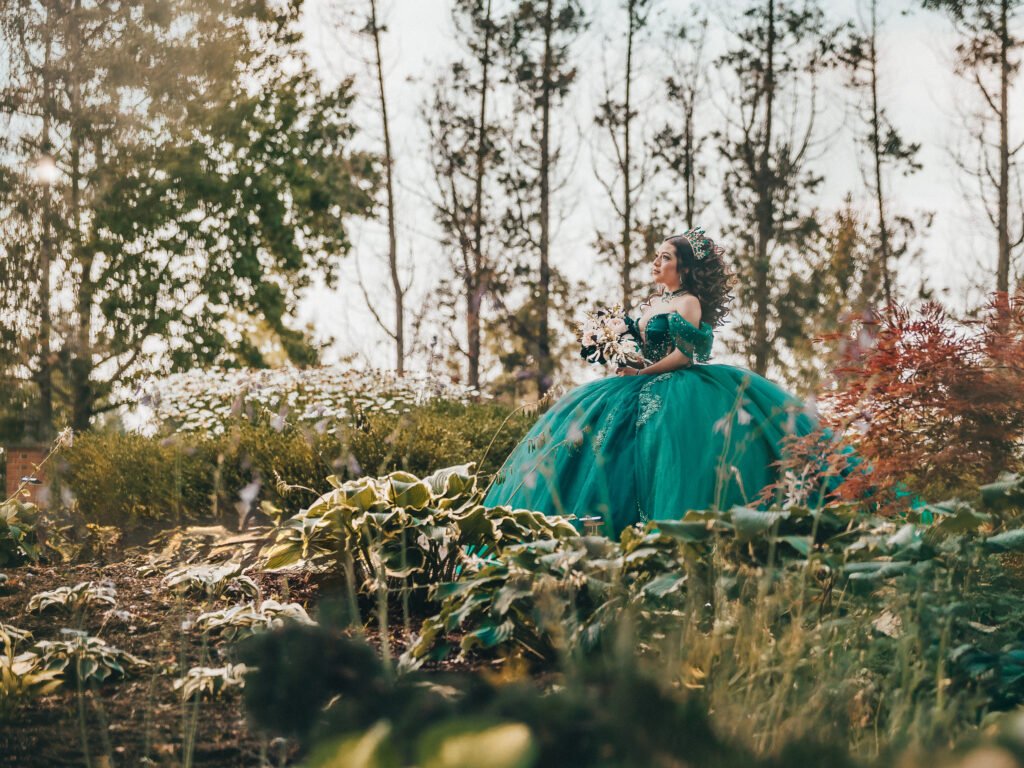 Dreamy Quinceanera in emerald dress gazing up, cinematic moody lighting and fine art aesthetic at Coxhall Gardens.