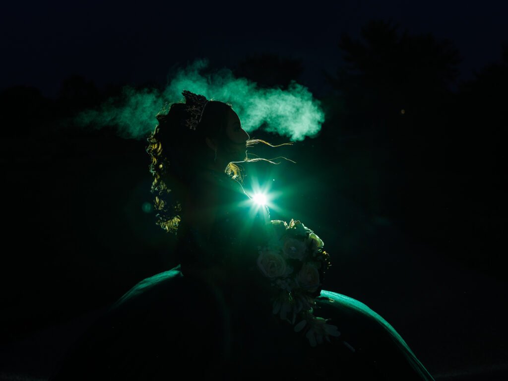 Silhouette of Quinceanera with emerald green smoke and dramatic starburst backlight, fine art night portrait in Carmel.