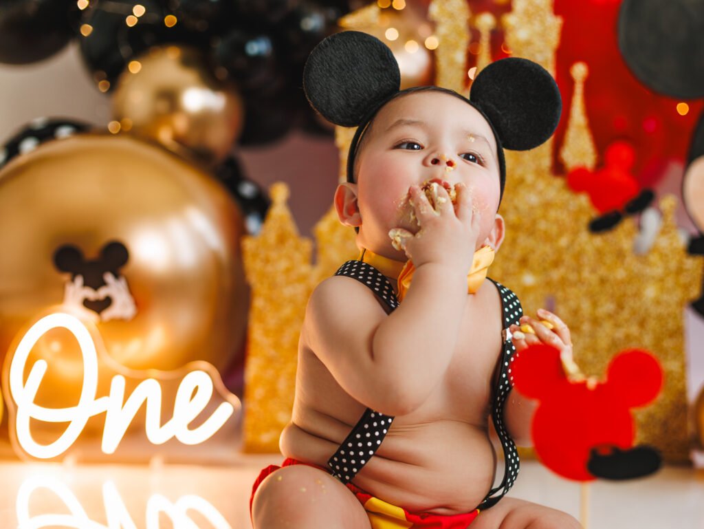 Close-up of a first birthday boy enjoying his cake during Mickey Mouse Cake Smash Photography