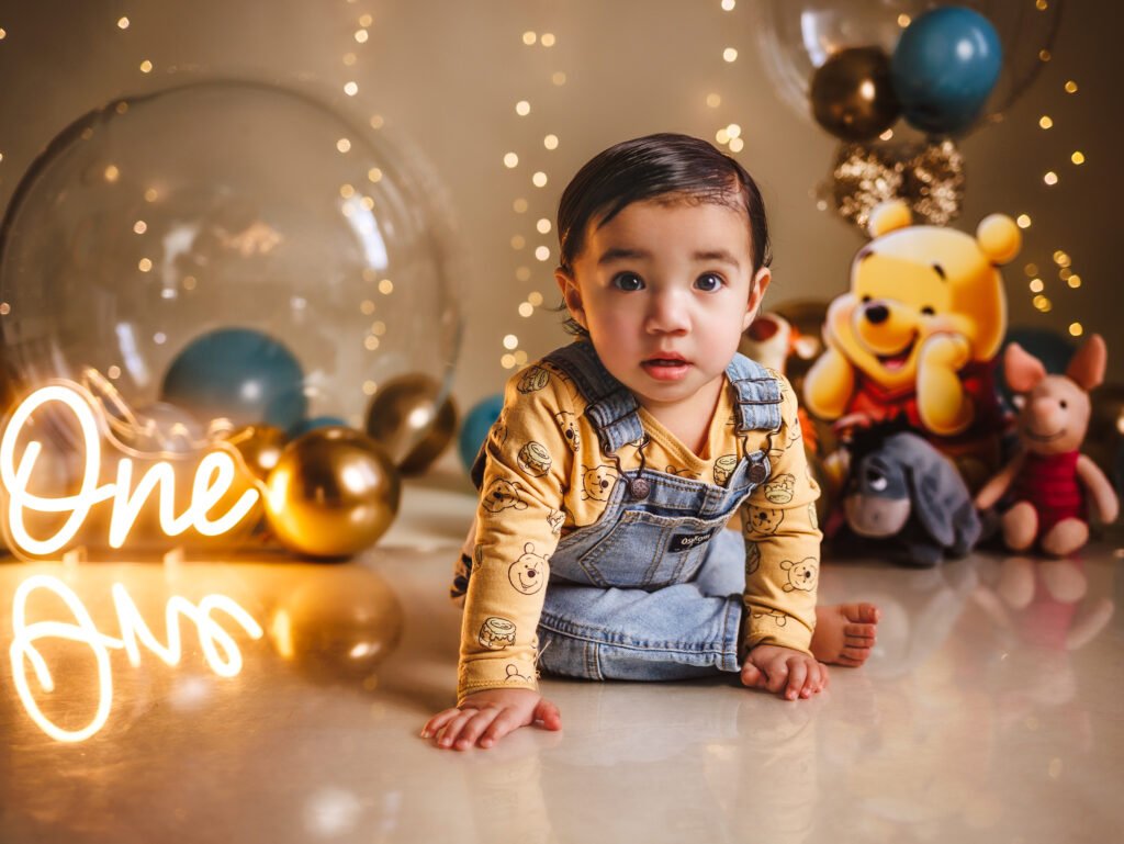 Happy baby boy in a Winnie the Pooh denim overall for his Fine Art Indianapolis Cake Smash session.