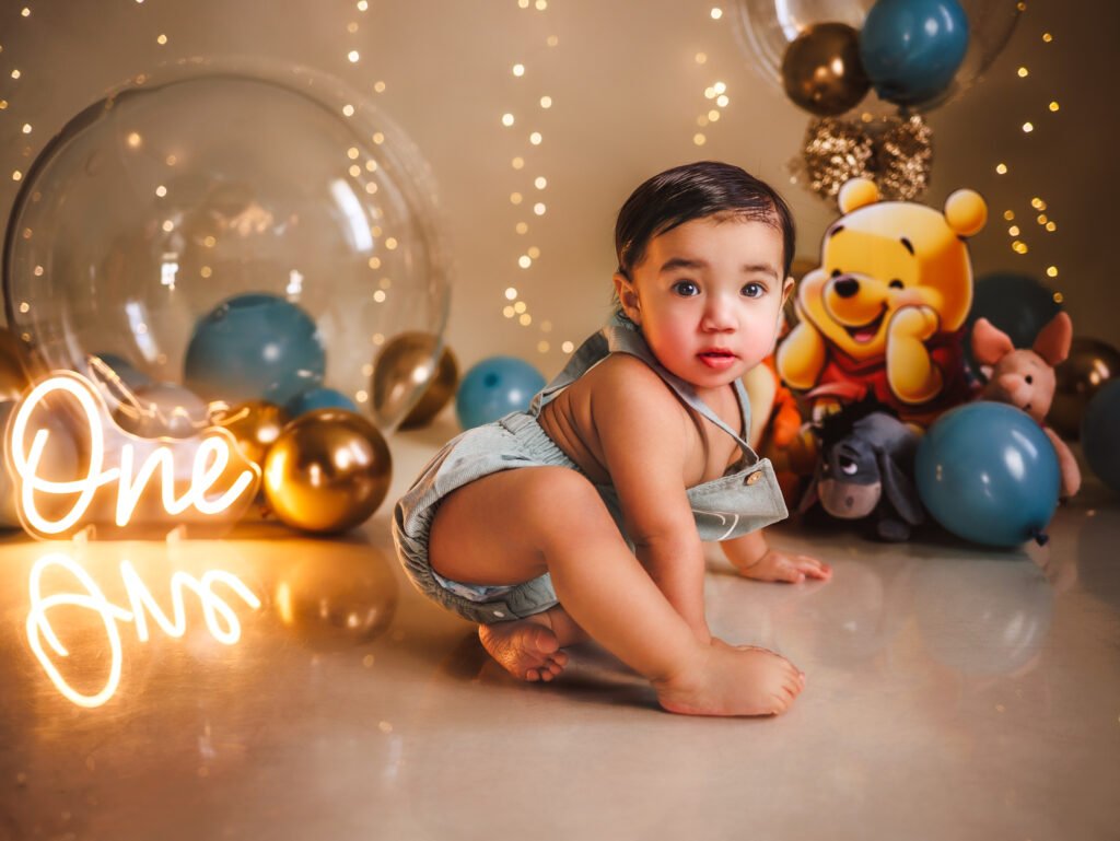 Curious toddler sitting on reflective floor, cinematic warm bokeh and Winnie the Pooh decor in Indianapolis studio