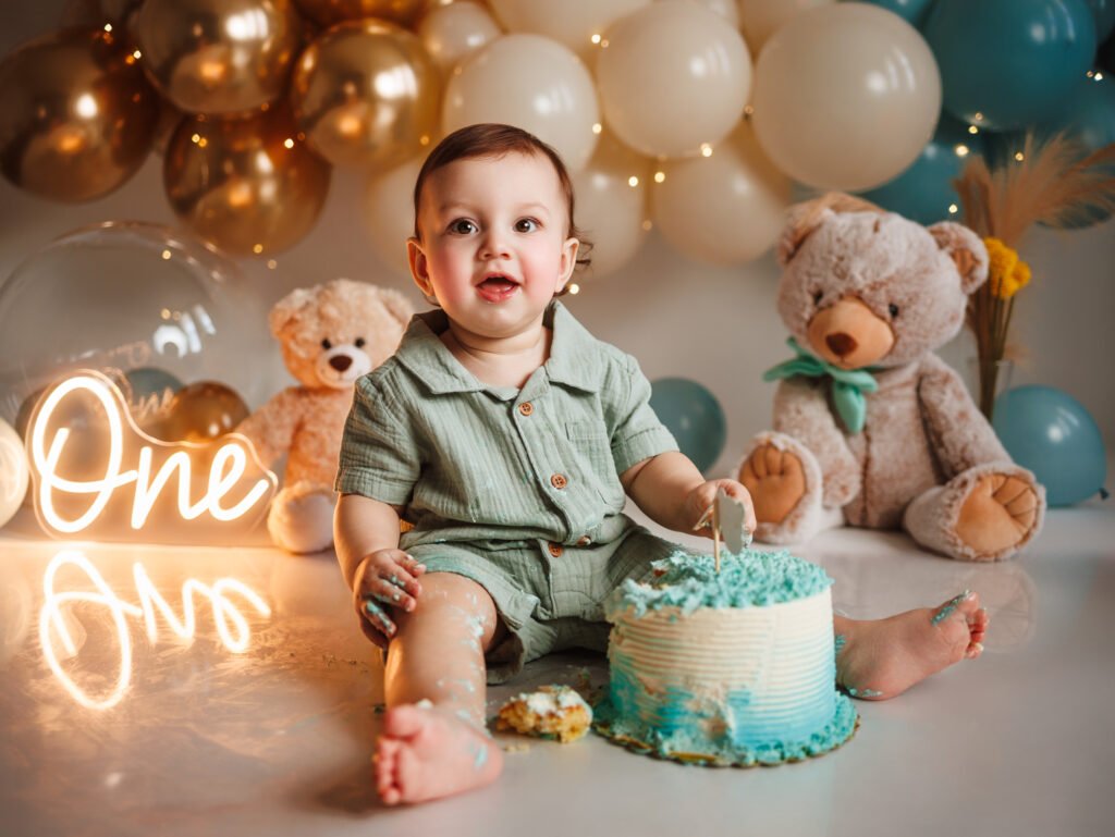Smiling baby boy with blue cake and teddy bears, fine art aesthetic with cinematic warm glow in Indianapolis.