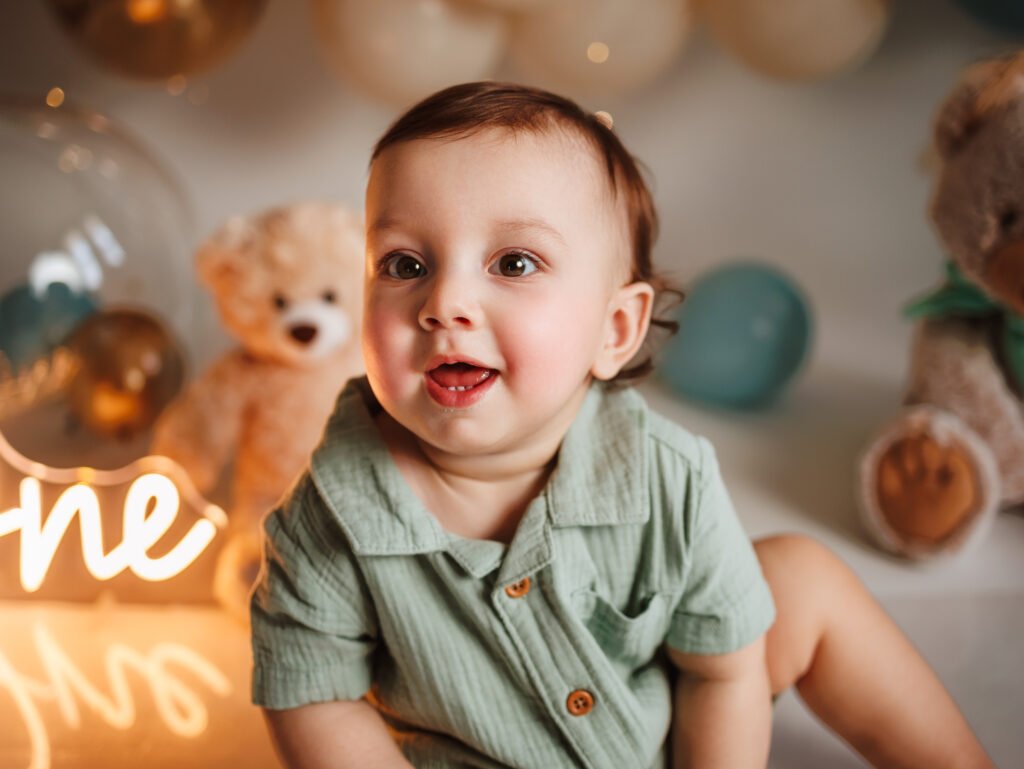 Smiling baby boy in sage shirt, fine art birthday aesthetic with cinematic warm lighting in Indianapolis studio.