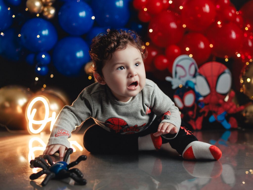 One-year-old boy playing with a toy spider during his Spider-Man Cake Smash Photography session in Indianapolis.