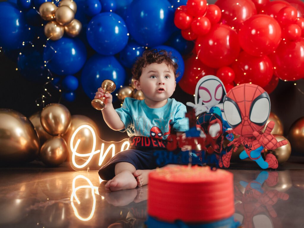 Adorable baby boy tasting his birthday cake during a Spider-Man Cake Smash Photography shoot.