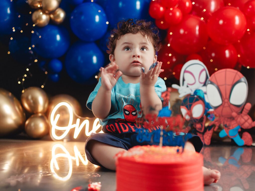 Happy toddler celebrating his first birthday with Spider-Man Cake Smash Photography by Gabby Aguirre.